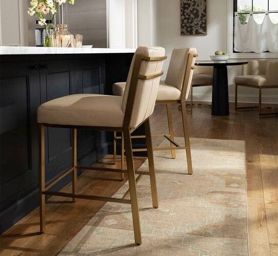 Brass and leather counter chairs beside black kitchen island