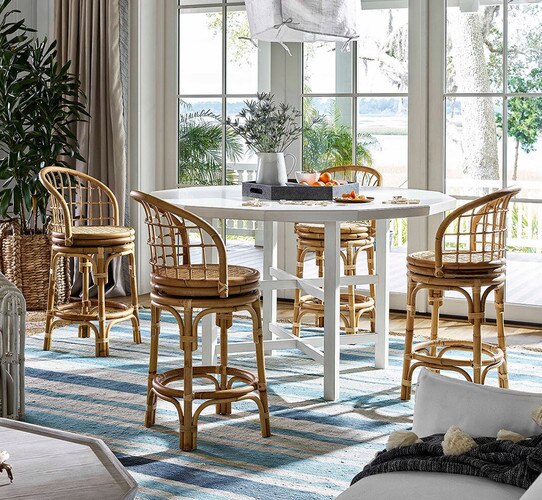 Coastal dining room with round white dining table and four rattan stools