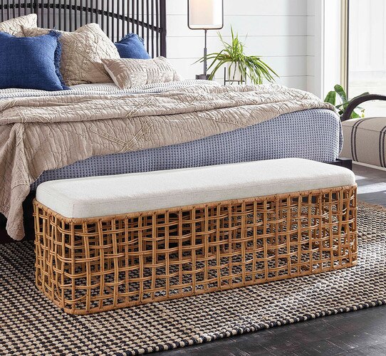 Bedroom with black bed frame and rattan stool at the foot of the bed