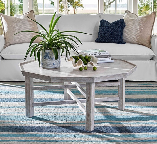 Wood octagonal coffee table holding a potted plant and bowl of limes