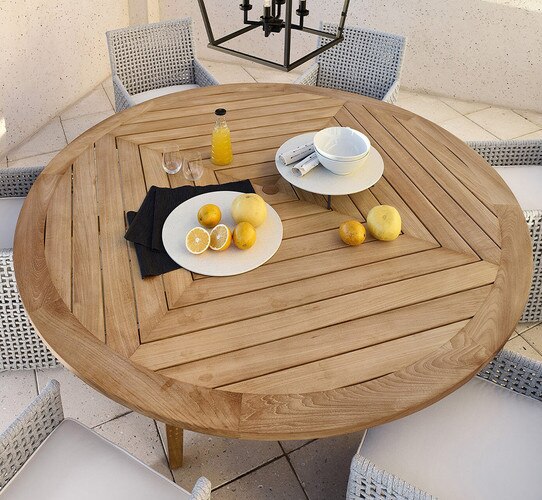 Circular outdoor wood table with gray chairs around it and a plate of lemons in the center