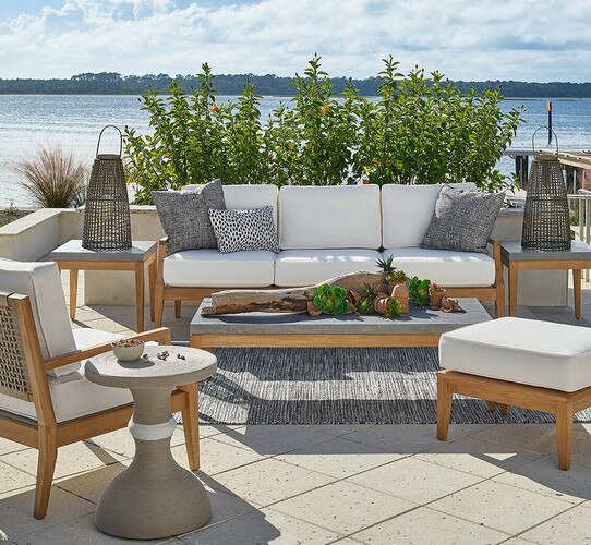 Concrete and wood outdoor coffee table on a patio surrounded by a sofa and chairs