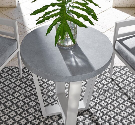 Metal patio table with a clear glass vase with a palm leaf in it