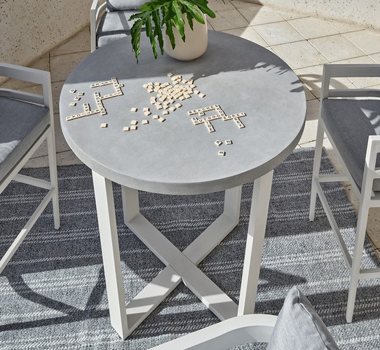 Bar table with scrabble surrounded by white and gray bar chairs