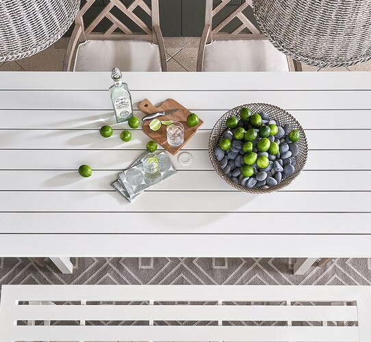 White outdoor dining table with a bottle of tequila and bowl of limes