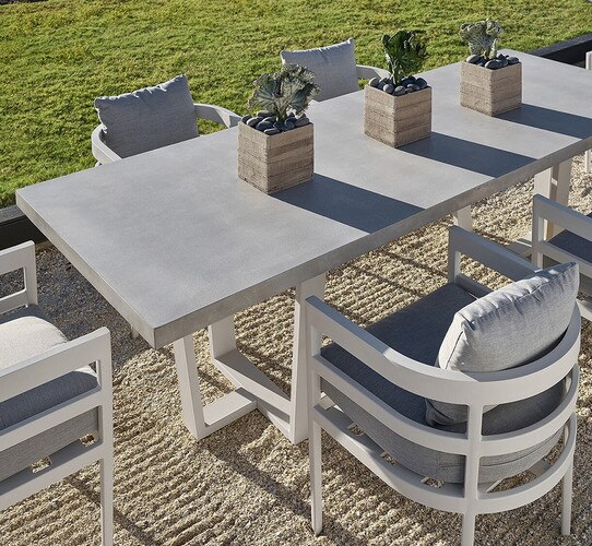 Concrete dining table on a sand patio with chairs around it