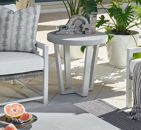 Concrete and metal side table on a patio beside a white sofa