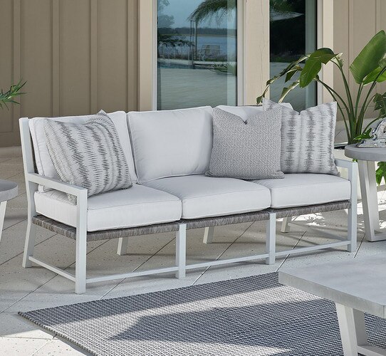 White and metal outdoor sofa on a patio beside a potted palm plant