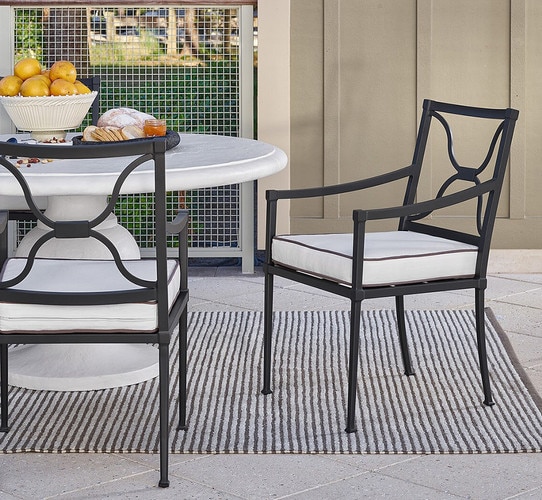 Black metal outdoor chair on a patio beside a white outdoor table