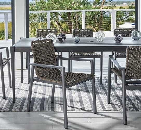 Woven chairs around a rectangular metal table on a patio