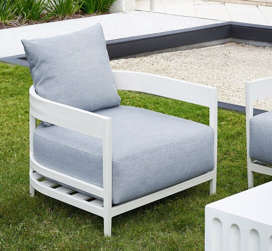 White and linen outdoor chair sitting on a lawn