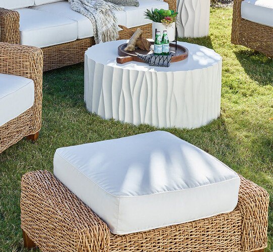 Wicker and linen ottoman next to a circular white coffee table