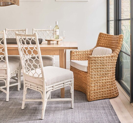 Wicker chair with white cushions at a wood dining table