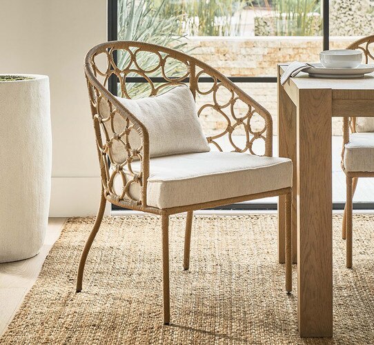 Woven dining chair with white cushions on a jute rug