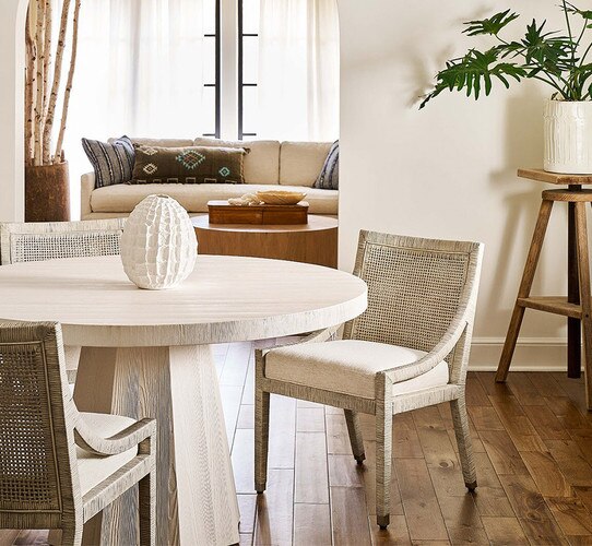 Circular wood dining table with three chairs in a dining room