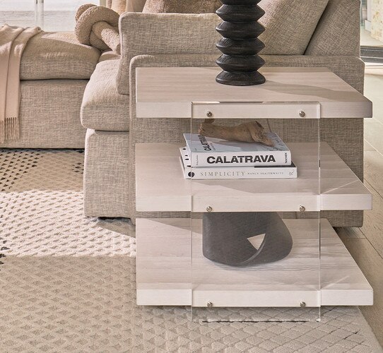 Wood and acrylic three-tiered side table holding dÃ©cor and a black lamp