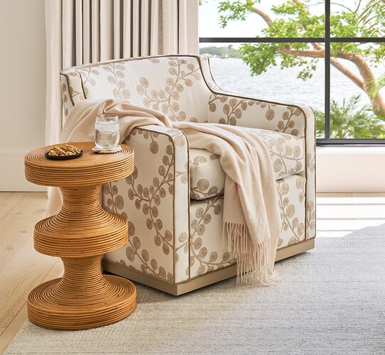Rattan side table beside a white floral accent chair
