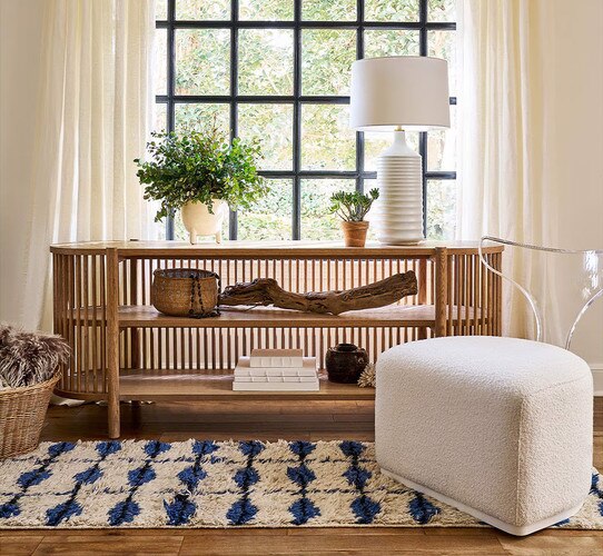 Wood credenza in front of a mirror holding dÃ©cor, plants, and a lamp