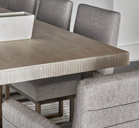 Corner of a wood dining table with gray dining chairs