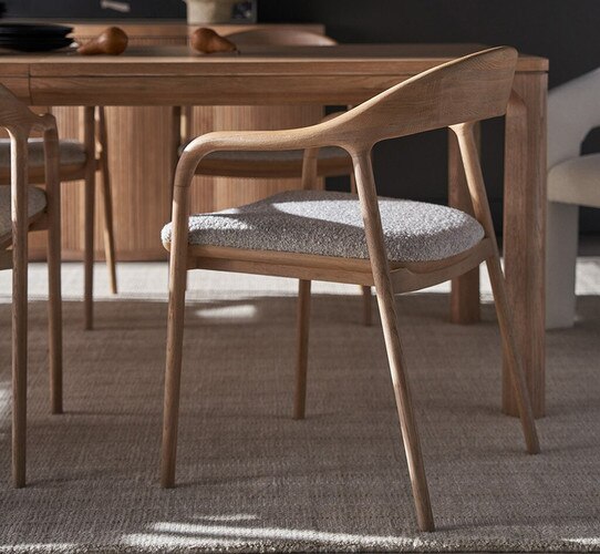 Wood open back dining chair with a linen seat beside a wood dining table