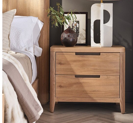 Wood nightstand holding a black lamp next to a bed holding a white lamp