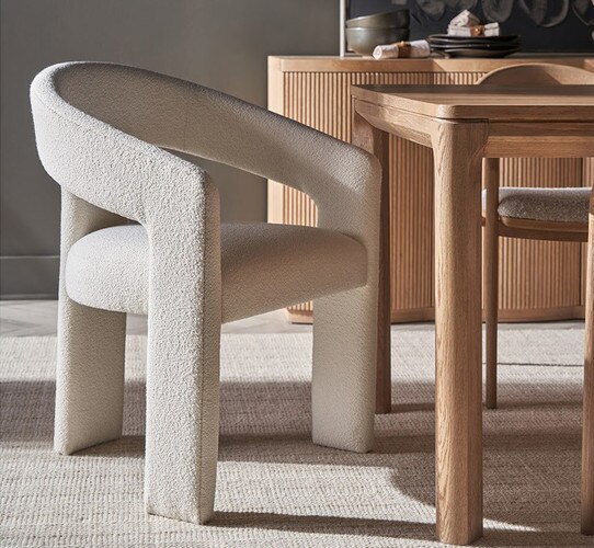 White three-legged linen dining room table beside a wood dining table