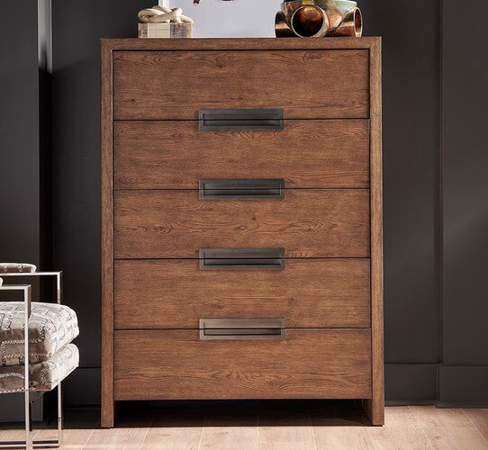 Tall wooden dresser with inlaid metal handles in front of a black painted wall