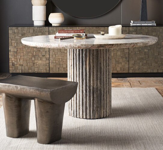 Marble circular dining table holding books and a tray with a large candle