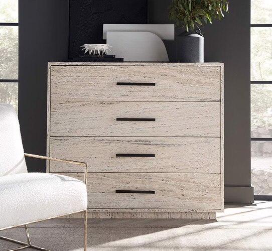 White wood dresser with black metal tables with books and a black vase