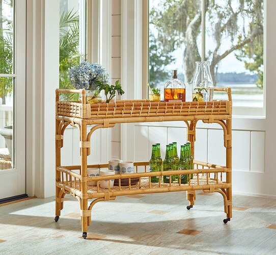 Wicker bar cart holding liquor bottles and mugs