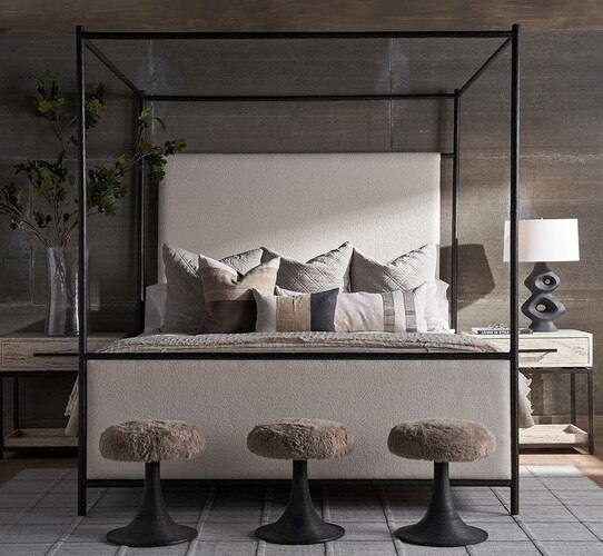 Black and linen bed with three shag stools in front of it