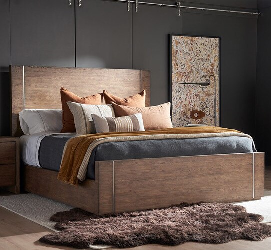 Wood bedframe with orange and blue pillows and blankets
