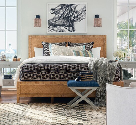 Rattan bed frame with a black and white abstract painting above it