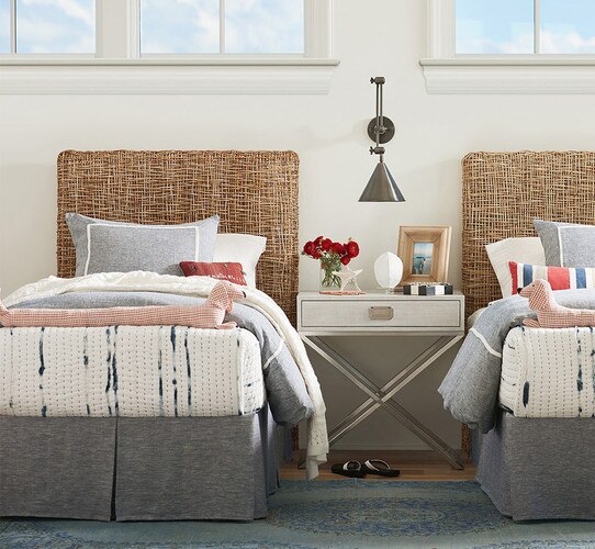 Woven twin beds with a nightstand separating the two