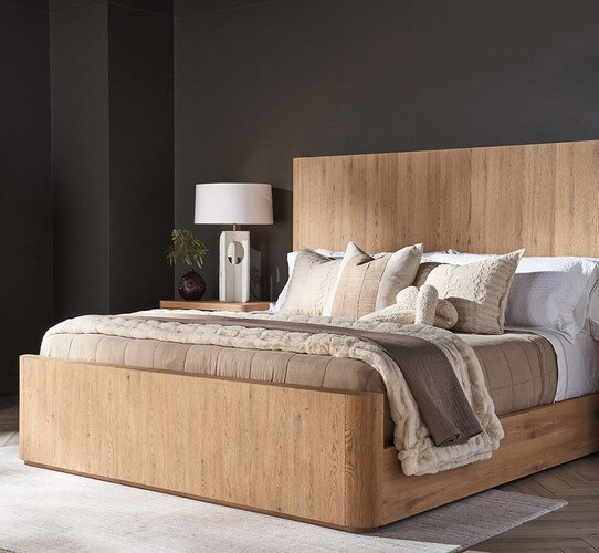 A black painted bedroom with a wood bedframe and nightstand holding a white lamp