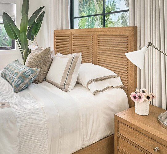 Wood bed frame with white linen sheets beside a wood nighstand