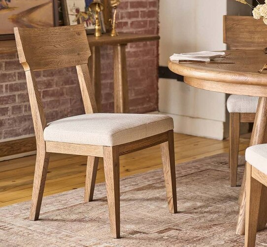Wood dining chair with fabric seat beside a circular wood dining table