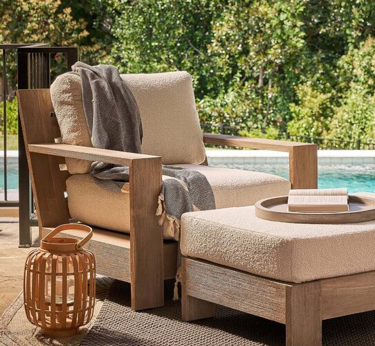 Teak outdoor chair beside a rattan hurricane candle holder