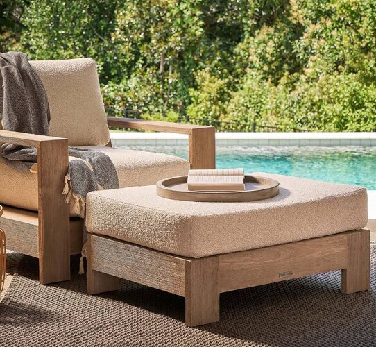 Teak ottoman with plush cushion holding a tray with a book