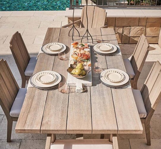 Outdoor teak table with table settings and a charcuterie board