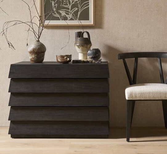 Dark wood dresser beside a black and white accent chair