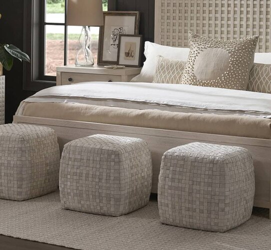 Three white footstools at the foot of a white bed