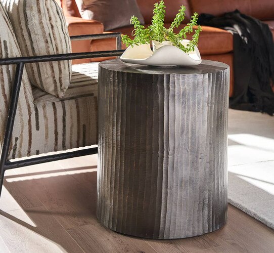 Metal cylinder side table holding marble planter with green plant