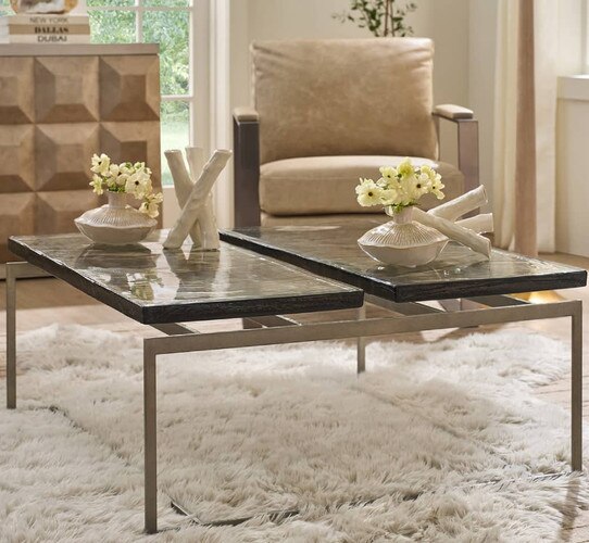 Glass and metal coffee table holding flowers and marble sculpture