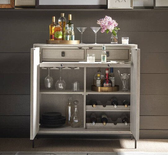 Open bar cabinet with glasses flowers and bottles of liquor