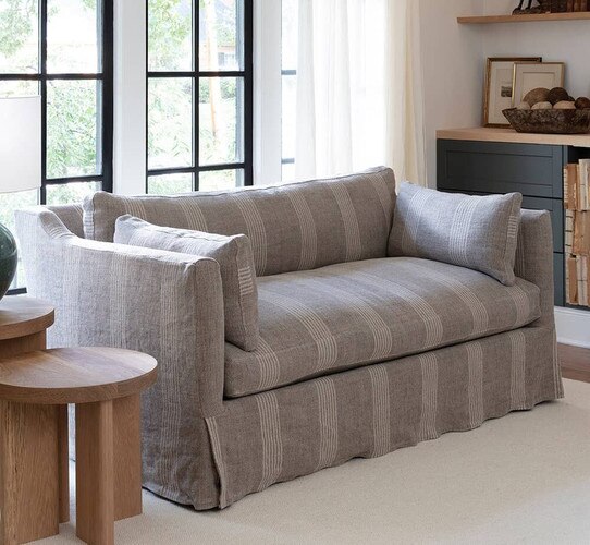 Striped brown sofa in front of two tall black framed windows