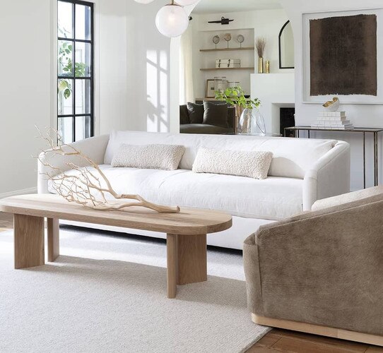 Living room with white sofa and oval wood coffee table holding a branch