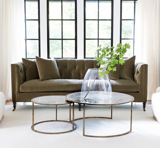 Green sofa with two circular nesting coffee tables in front of it