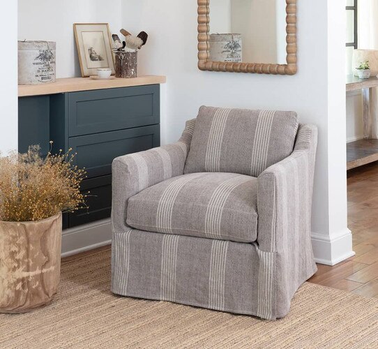 Slip cover chair below a wood mirror and beside built in shelving