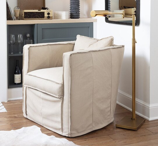 Suede swivel arm chair beside floor task lamp